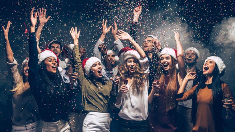 young people wearing santa hats celebrating with confetti
