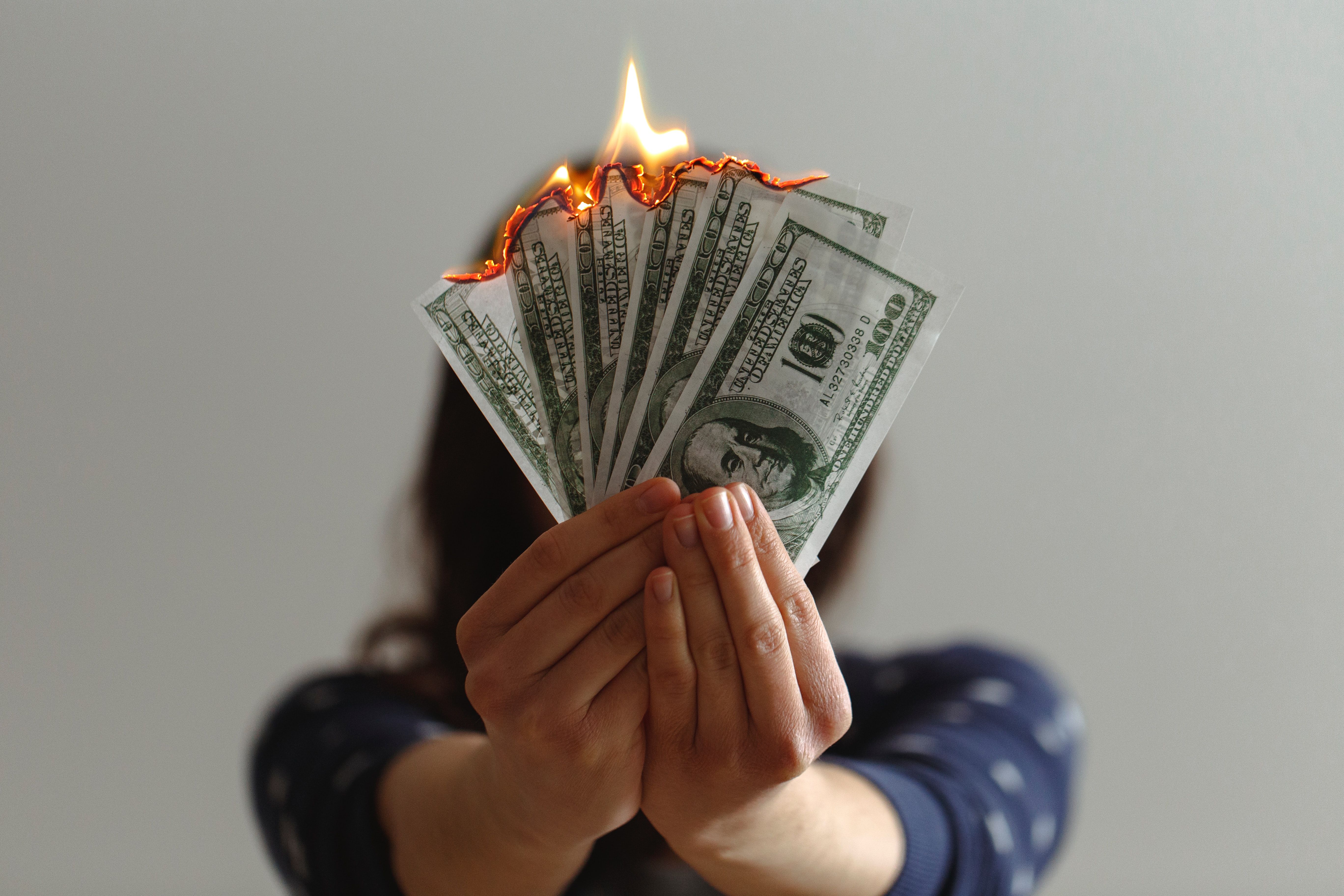 photo of cash burning as woman holds it -- for inflation poll