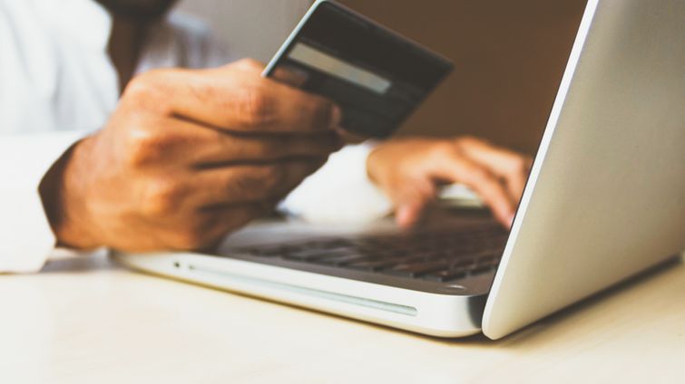 man on laptop holding credit card showing concept of increasing online sales