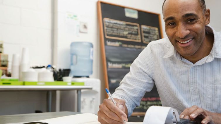 smiling man crunching numbers at his small business as he creates new revenue streams