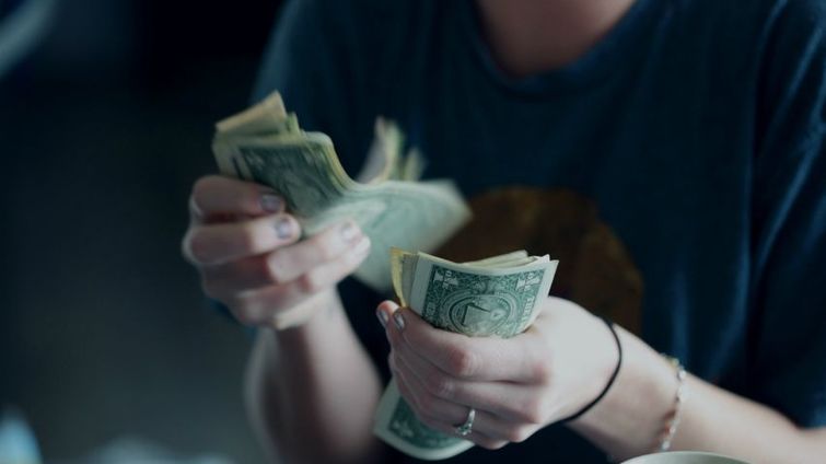 woman at a small business counting money trying to cut costs coronavirus