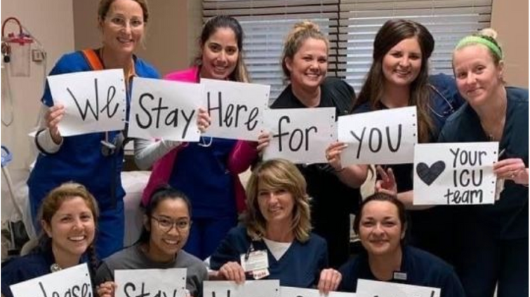 group of female nurses holding up a sign about protecting people during coronavirus