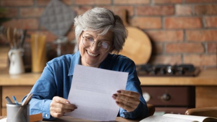 older woman smiling at ppp loan forgiveness application form