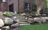 Boulder Retaining Wall with integrated staircase. by RRR Lawn & Landscape LLC