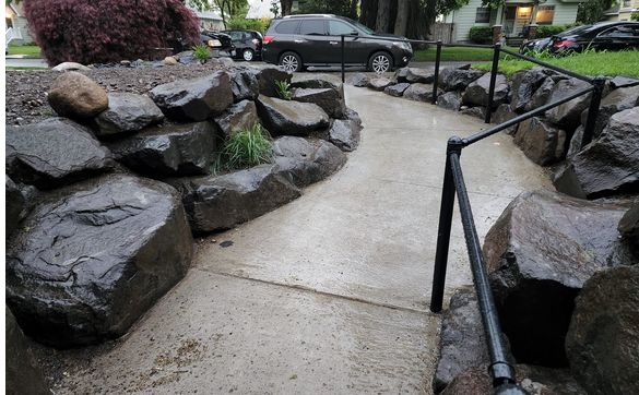 Boulder retaining wall addition, concrete ada ramp with Black railing and a hipp addition to home by Tessitore