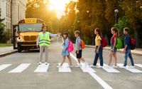 A crossing guard is helping children cross the street safely. by Prime Time Bus Co., Inc