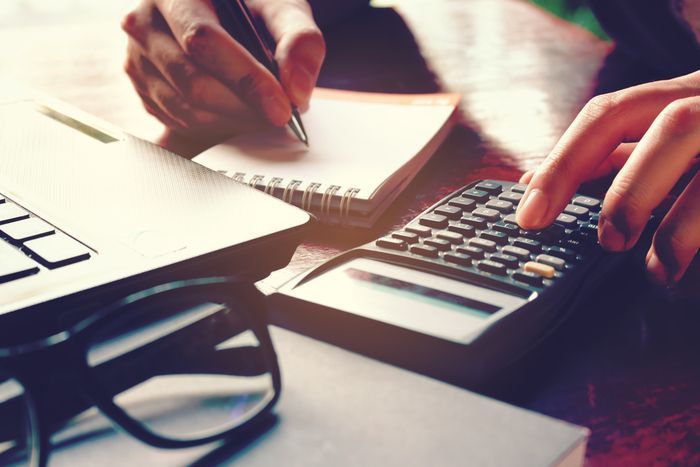 woman calculating business expenses on calculator and paper