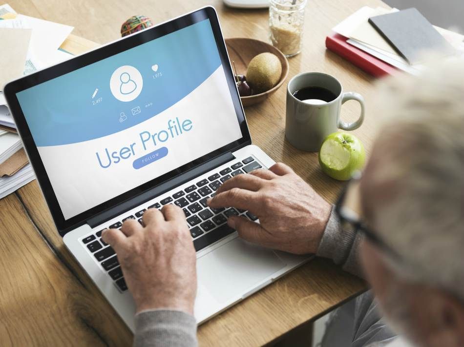 older man sitting at laptop filling out user profiles on online networking sites