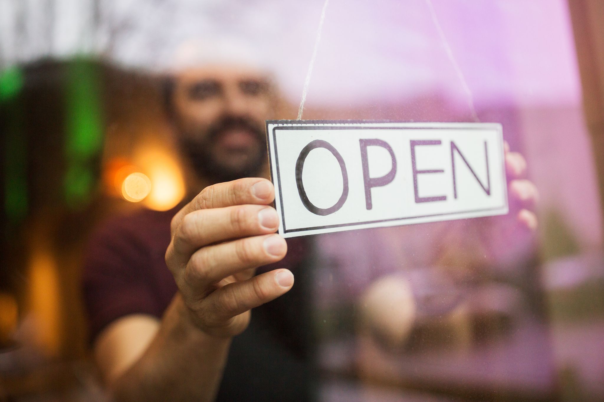 man putting open sign on door after receiving CARES Act funds | Alignable