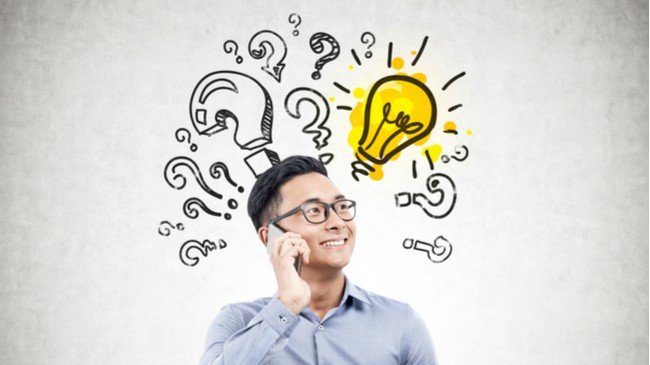 man in blue shirt on smart phone with question marks and exclamation marks behind him