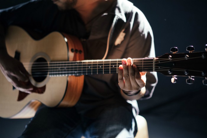 person playing acoustic guitar sitting down | 10 Unique Online Business Ideas to Start from Home