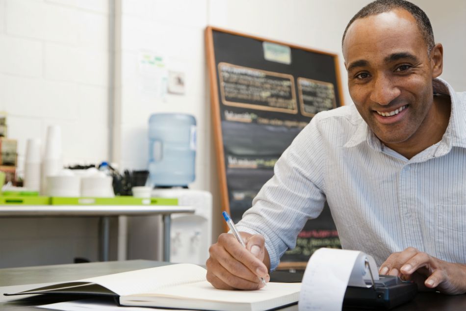 smiling small business owner crunching numbers to create new revenue streams