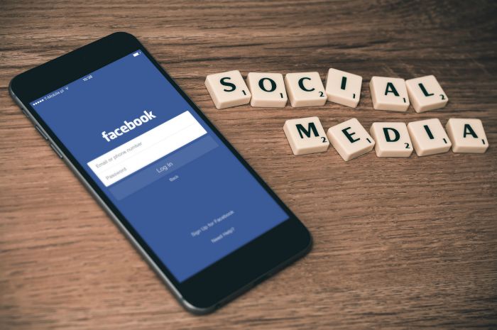 social media scrabble tiles on table with facebook on smartphone