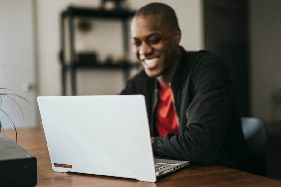 small business owner sitting at table looking at laptop smiling while online networking