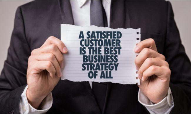 a satisfied customer is the best business strategy of all quote on paper with man holding | 6 Customer Service Trends Your Small Business Needs in 2020