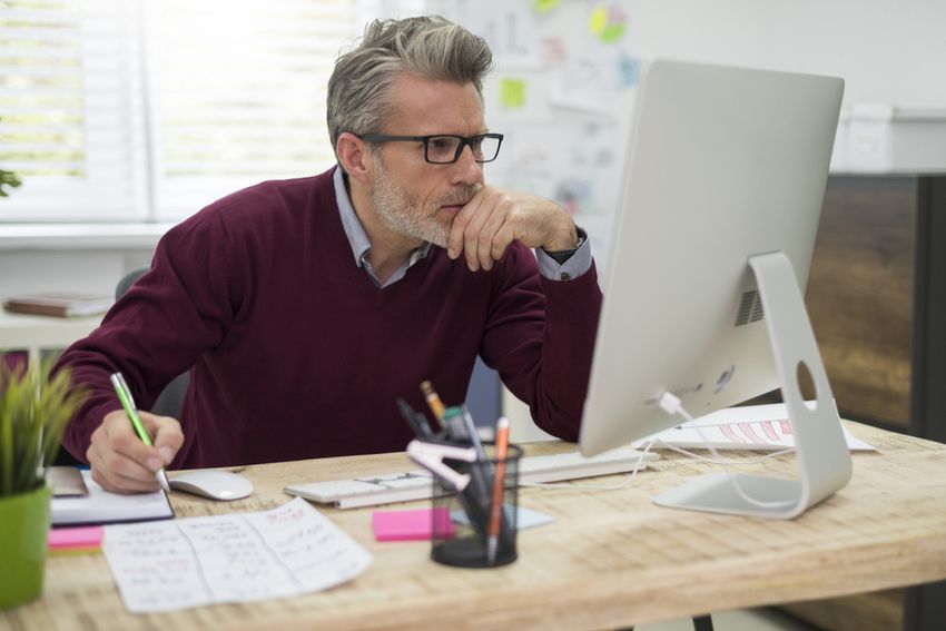 pensive man looking at computer calculating ppp loan forgiveness amount